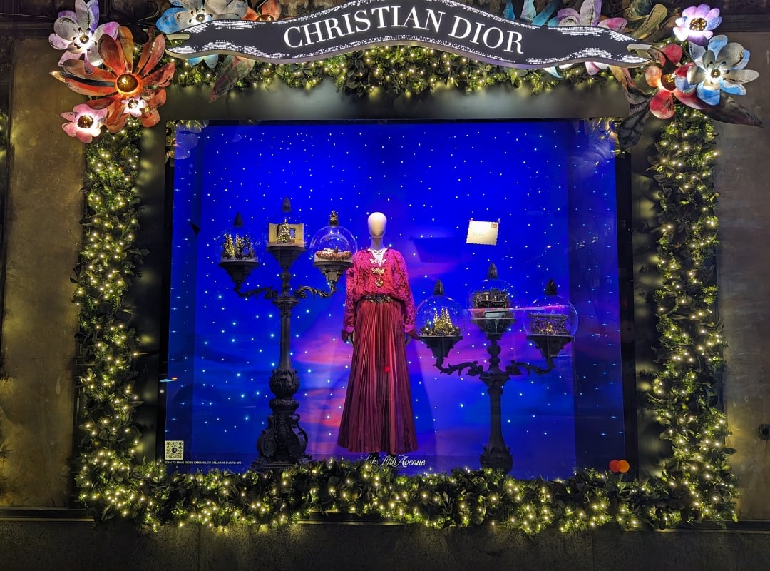Dior Christmas window at shopping mall featuring a red outfit and old fashioned street lamps.