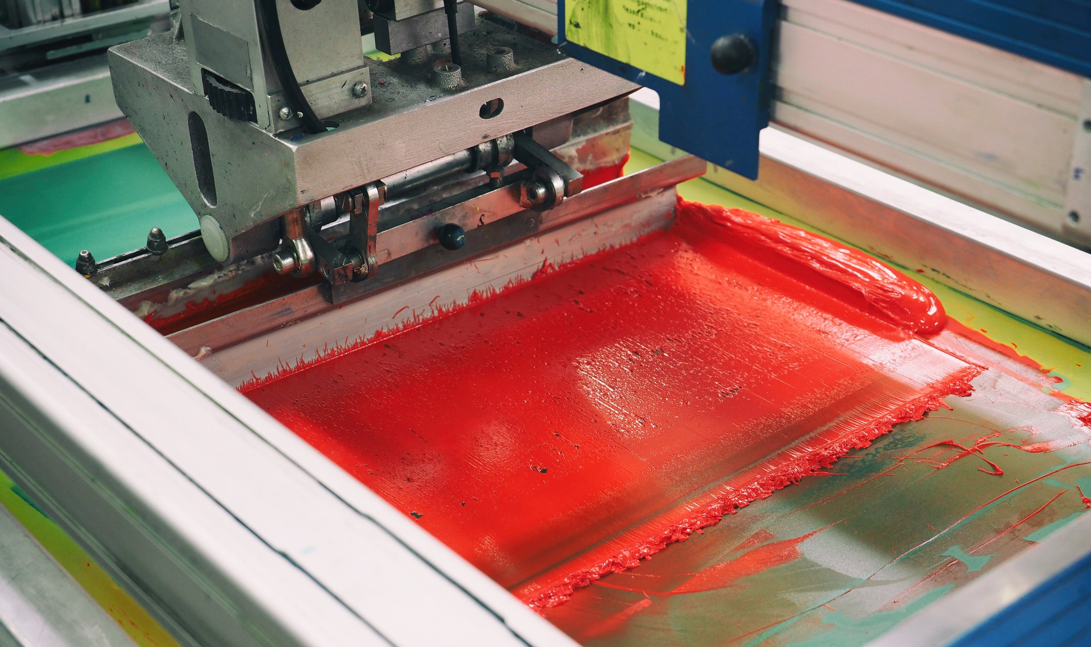 Screen Printing machine in the painting stage layering the color red.