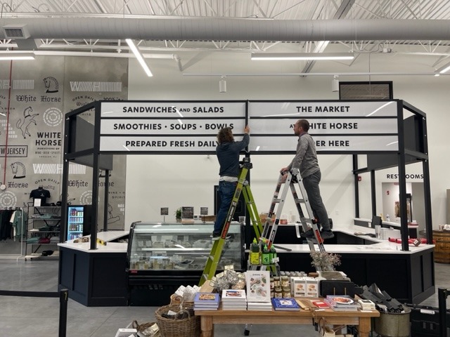 White Horse Wine and Spirits. Signage of menu above food stall inside market building. front view during installation.